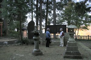石碑の前で神社のいわれを説明するWさん
