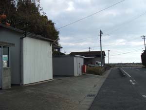 バス停南の電柱後方の倉庫様建物裏に地蔵
