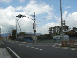 点滅の信号機のある交差点右手の松林にいぼ地蔵尊