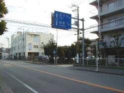 青い道路標識の後方に椿地蔵あり。